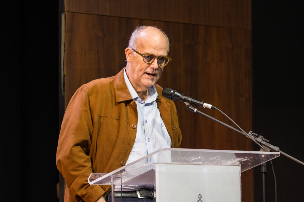 Professor Mozahir Salomão Bruck discursando atrás do púlpito no palco.