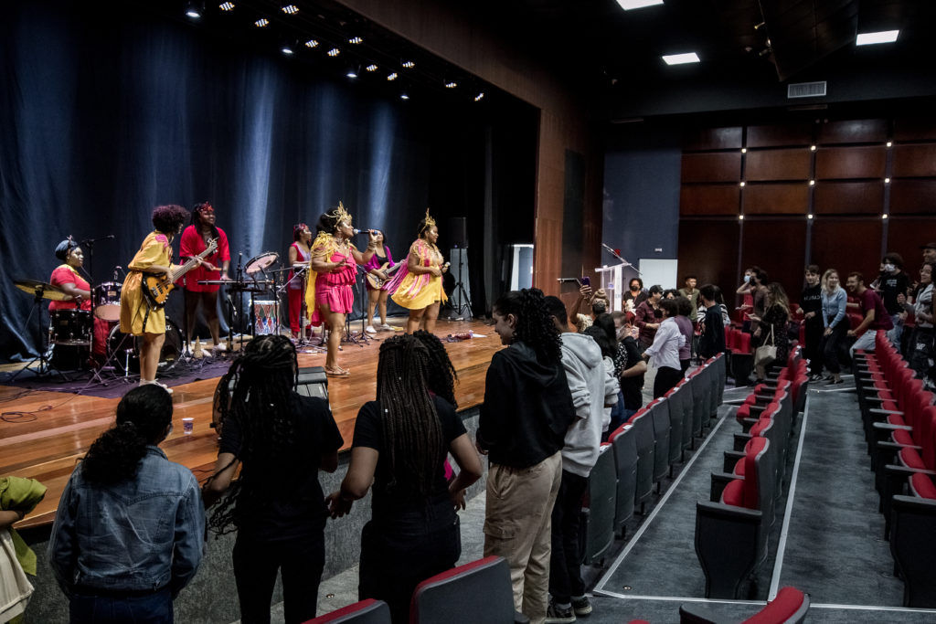 Alunos, professores e funcionários dançando em frente ao palco