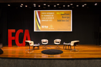 Palco com quatro cadeiras, logo grande da FCA e uma projeção do convite do evento.