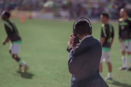 Repórter em campo cobrindo jogo de futebol