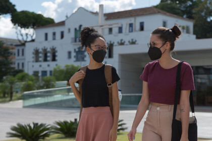 Duas jovens estudantes usando máscara posam no campus Coração Eucarístico